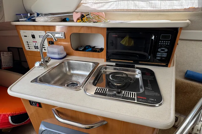 Slide: The Image of 2002 Bayliner 2455 Ciera boat kitchenette with sink, stove, and microwave. - 14