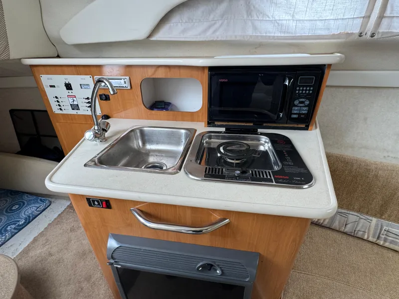 Slide: The Image of Compact kitchen area in a 2002 Bayliner 2455 Ciera boat with sink, stove, and microwave. - 30