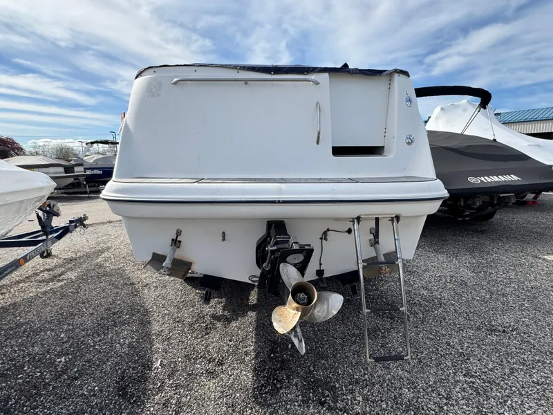 Slide: The Image of 2002 Bayliner 2455 Ciera boat, rear view with propeller and ladder, parked on gravel. - 8