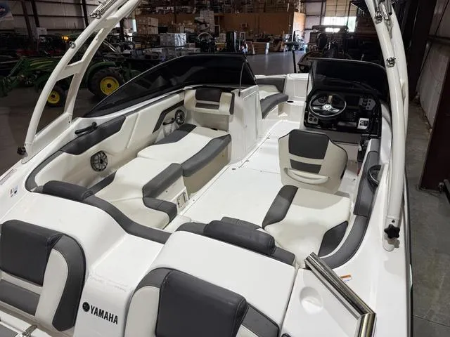 Slide: The Image of 2020 Yamaha AR210 boat interior with sleek seating and modern dashboard in a warehouse setting. - 10