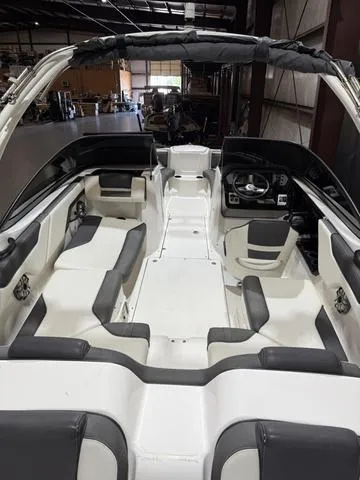 Slide: The Image of 2020 Yamaha Boats AR210 interior with sleek seating and modern dashboard in a warehouse setting. - 9