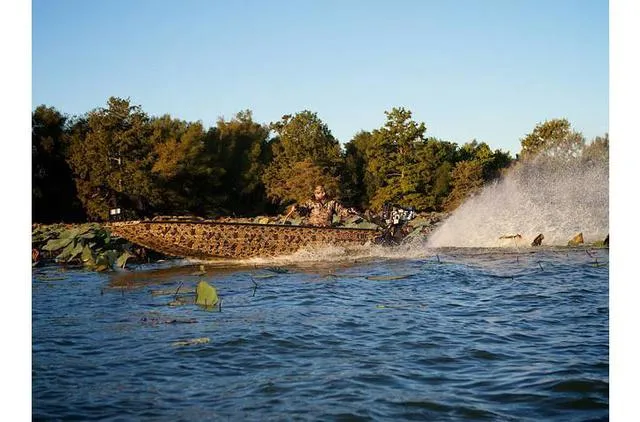 Slide: The Image of 2023 Excel Shallow Water F4 boat navigating through water with trees in the background. - 24