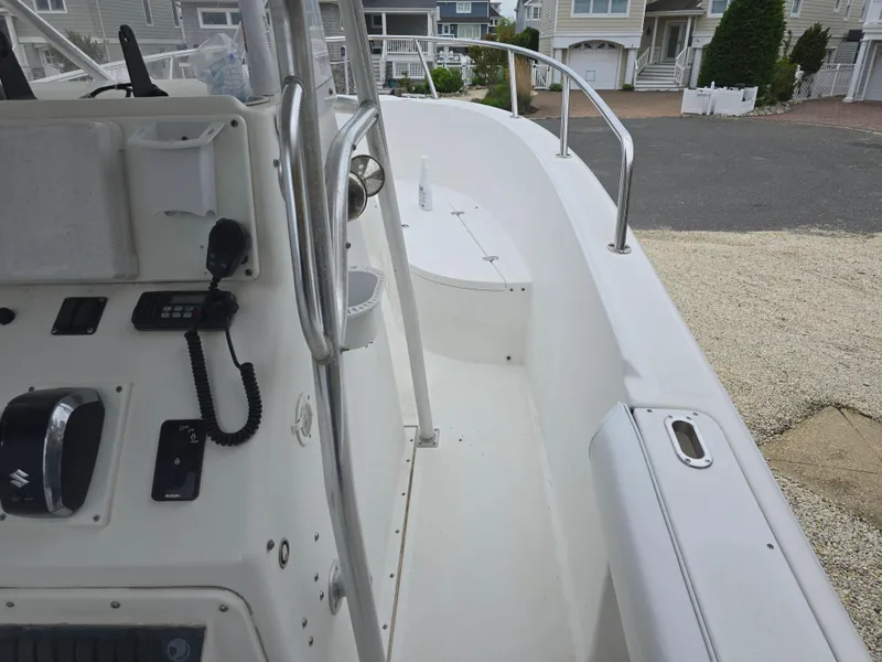 Slide: The Image of 2002 Edgewater 225CC boat on blocks near a house, featuring a white and blue hull. - 2