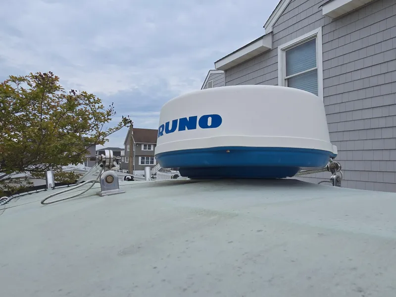 Slide: The Image of 2002 Edgewater 225CC boat docked in a residential area, showcasing its clean deck and steering console. - 4