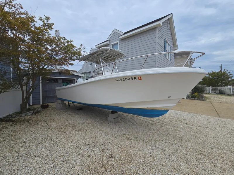 Slide: The Image of 2002 Edgewater 225CC boat on stands, parked near a house. - 7