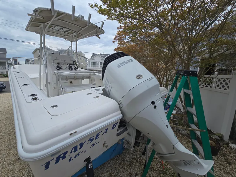 Slide: The Image of 2002 Edgewater 225CC boat on dry land near a house, overcast sky. - 8