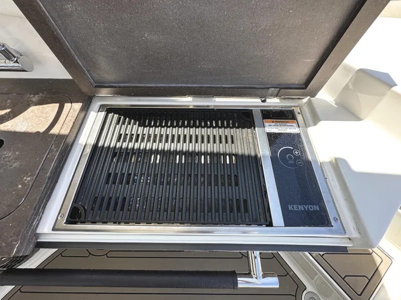 Slide: The Image of Built-in Kenyon grill on 2017 Sea Ray SLX 350 boat, open lid view. - 12