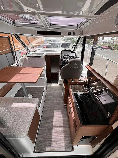 Slide: The Image of 2023 Jeanneau NC 895 interior with helm, dining area, and kitchenette. - 8
