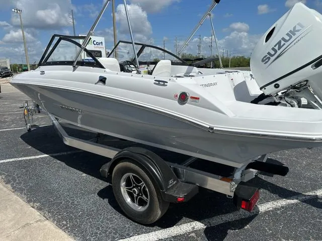 Slide: The Image of 2025 Stingray DC 191 boat with Suzuki engine on a trailer, parked outdoors. - 6