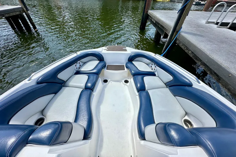 Slide: The Image of 2011 Yamaha Boats 242 Limited interior with blue and white seating, docked by water. - 12