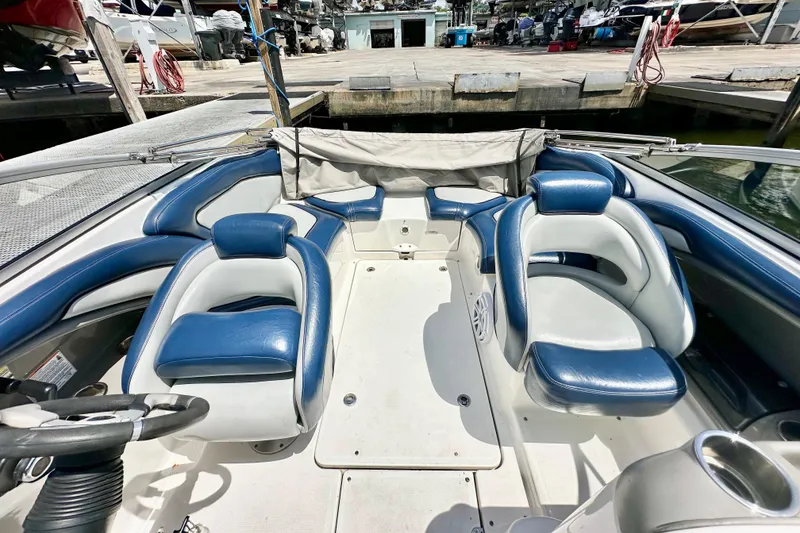 Slide: The Image of 2011 Yamaha Boats 242 Limited interior with blue and white seating at a marina. - 18