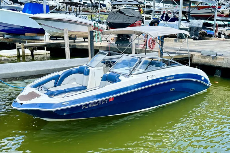 Slide: The Image of 2011 Yamaha Boats 242 Limited in marina, blue and white, docked with canopy. - 28