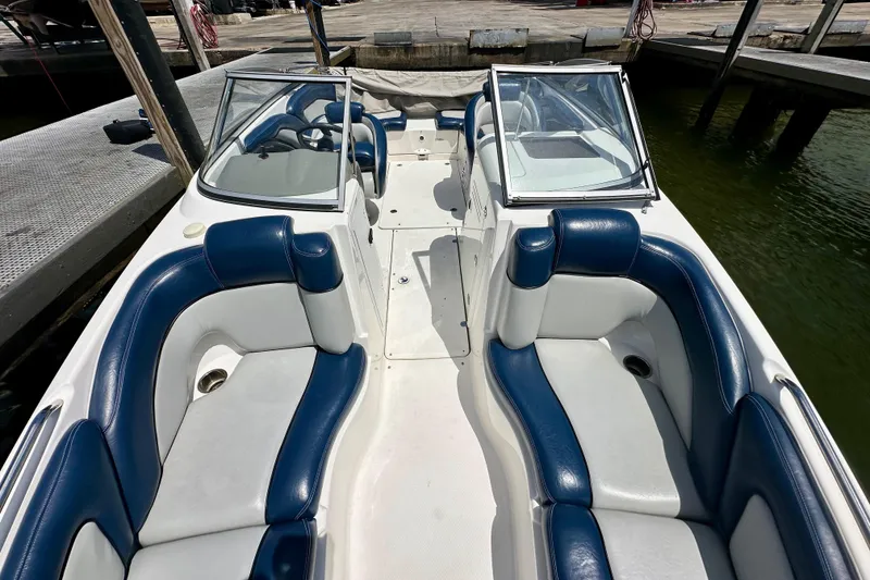 Slide: The Image of 2011 Yamaha Boats 242 Limited interior with blue and white seating, docked by the water. - 7