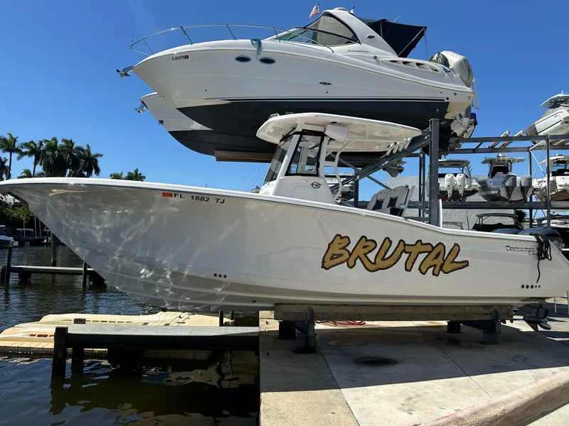 The Image of 2022 Tidewater 280 CC boat named "Brutal" docked at marina under clear blue sky. - 0
