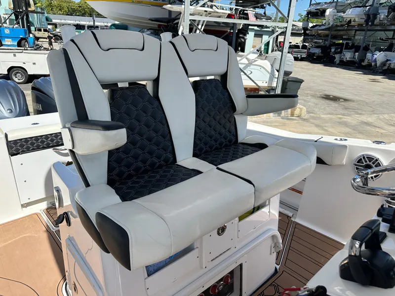 Slide: The Image of 2022 Tidewater 280 CC boat with dual cushioned seats and armrests in a marina setting. - 24