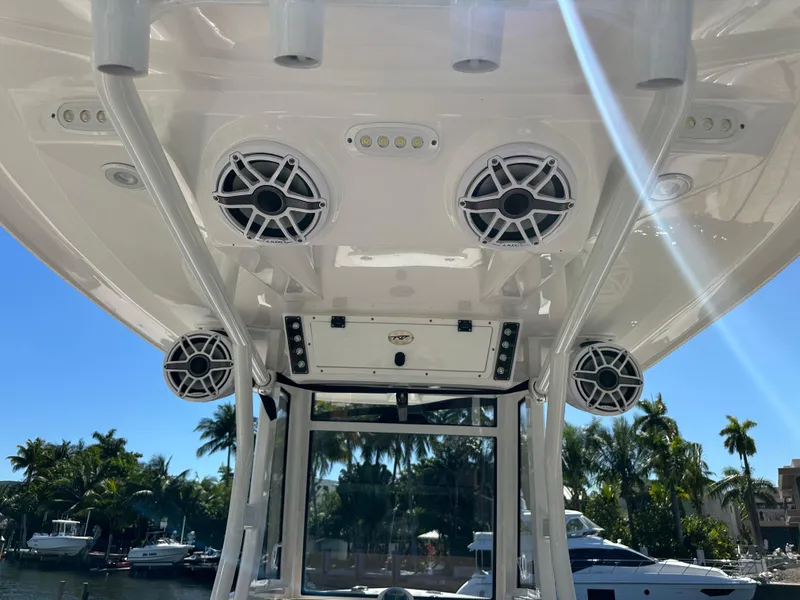 Slide: The Image of 2022 Tidewater 280 CC boat speakers and canopy, docked with palm trees in the background. - 27
