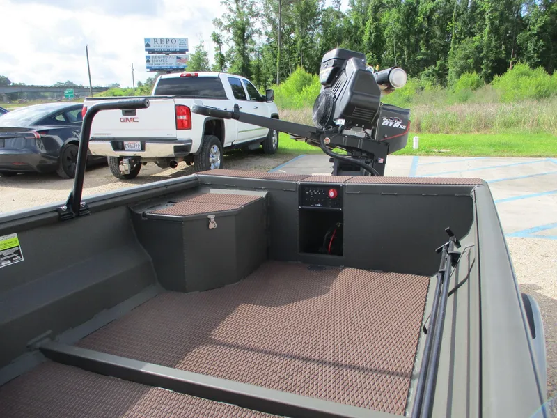 Slide: The Image of 2025 Gator Tail 1748 GATOR boat interior with motor, parked near trucks. - 6