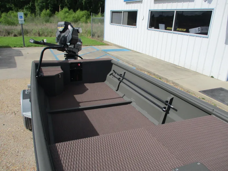 Slide: The Image of 2025 Gator Tail 1748 GATOR boat with spacious interior and motor, parked near a building. - 7