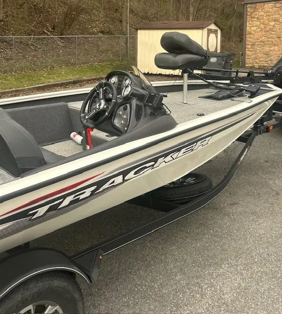 Slide: The Image of 2023 Tracker Pro Team 175 TXW boat with steering console and seating, parked outdoors. - 5