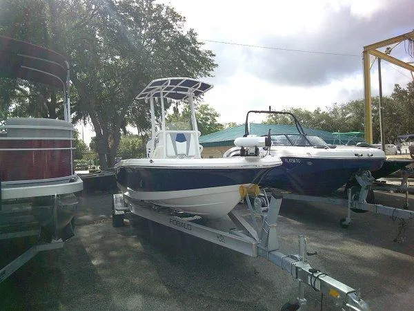 Slide: The Image of 2023 Robalo 206 Cayman boat on trailer, parked outdoors under cloudy sky. - 2