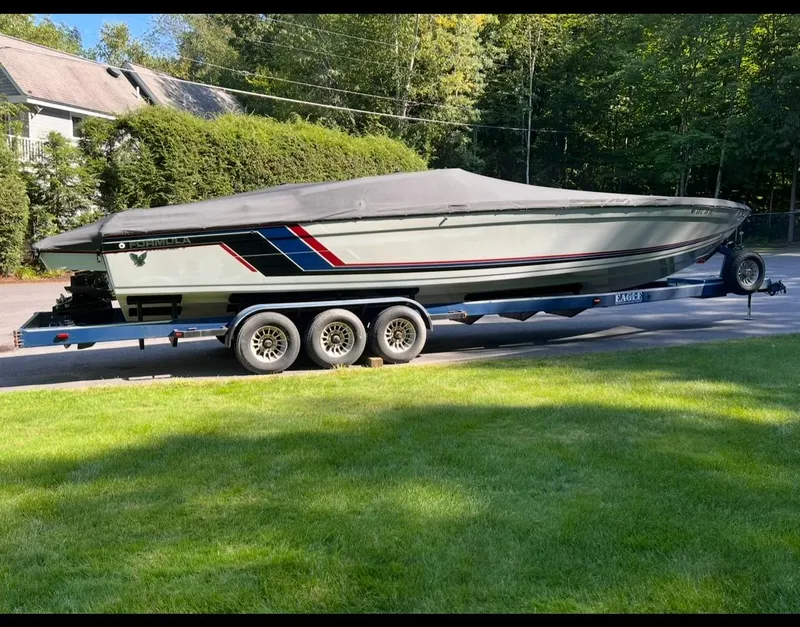 Slide: The Image of 1987 Formula 357 SR1 boat on trailer, covered, parked on driveway with lush greenery. - 3