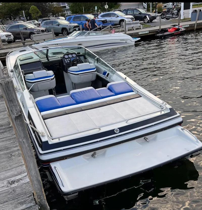 Slide: The Image of 1987 Formula 357 SR1 boat docked, featuring blue and white seating, on a calm waterfront. - 5