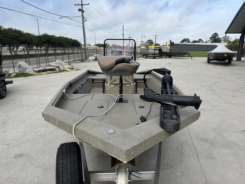 Slide: The Image of 2019 Alumacraft 18 Bay boat on trailer, parked outdoors, featuring a trolling motor. - 11