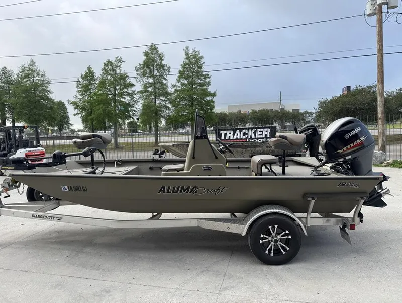Slide: The Image of 2019 Alumacraft 18 Bay boat on trailer with Yamaha outboard motor, parked outdoors. - 3