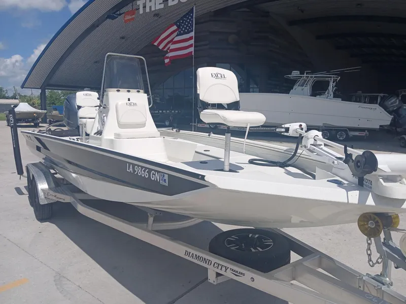Slide: The Image of 2022 Excel 220 boat on trailer, parked outside dealership with American flag. - 17