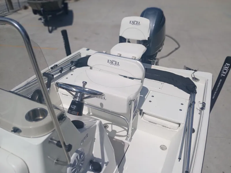 Slide: The Image of 2022 Excel 220 boat interior with steering wheel and seating, parked on concrete surface. - 5