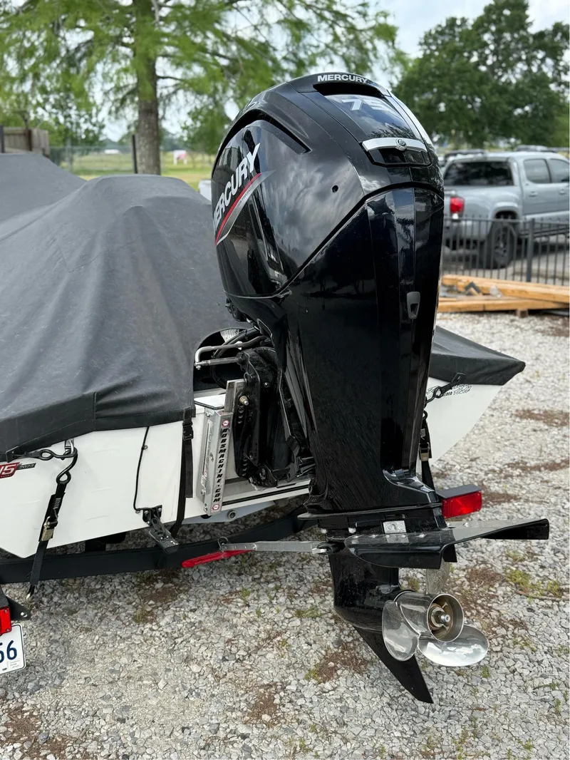Slide: The Image of 2023 Tracker Pro Team 175 TXW boat with Mercury outboard motor, covered and parked on gravel. - 6