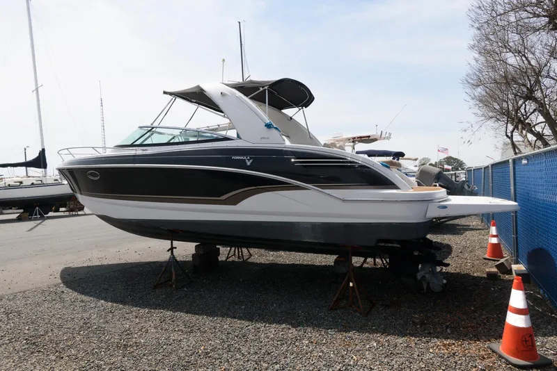Slide: The Image of 2012 Formula 290 Sun Sport boat on stands, parked outdoors near a blue fence. - 3