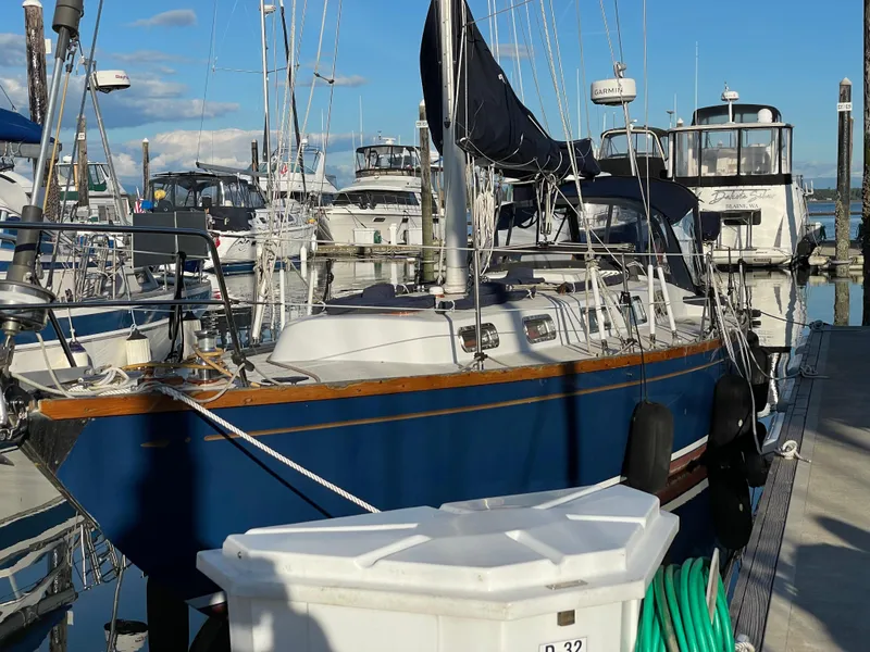 Slide: The Image of 1984 Ohlson 38 sailboat docked at marina, blue hull, clear sky background. - 13