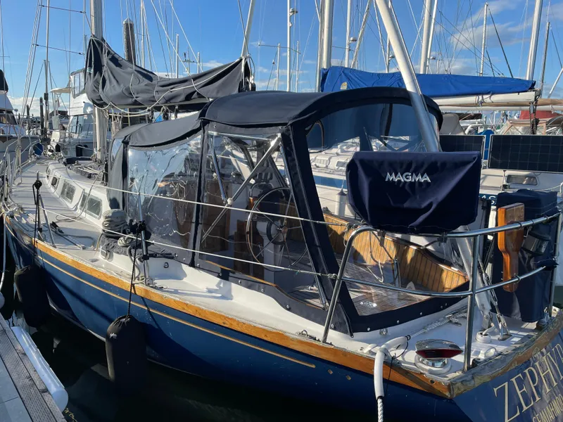 Slide: The Image of 1984 Ohlson 38 sailboat docked, featuring a blue hull and covered cockpit. - 14