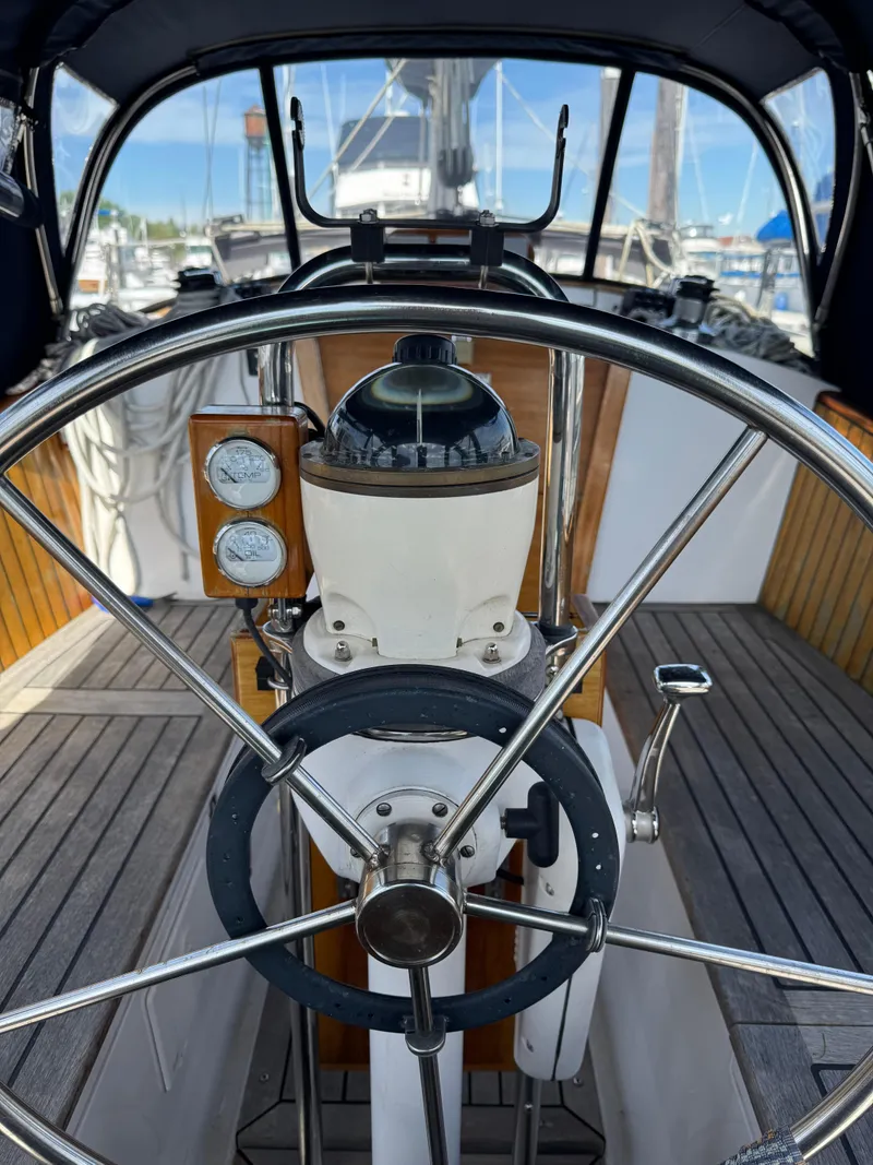 Slide: The Image of Steering wheel and compass on a 1984 Ohlson 38 sailboat, docked in a marina. - 19