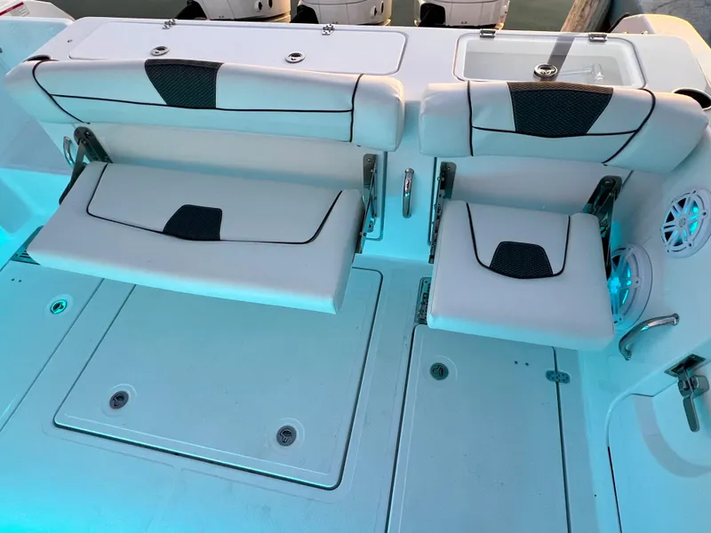 Slide: The Image of 2024 Wellcraft 352 Fisherman boat seating area with white cushioned seats and blue lighting. - 21