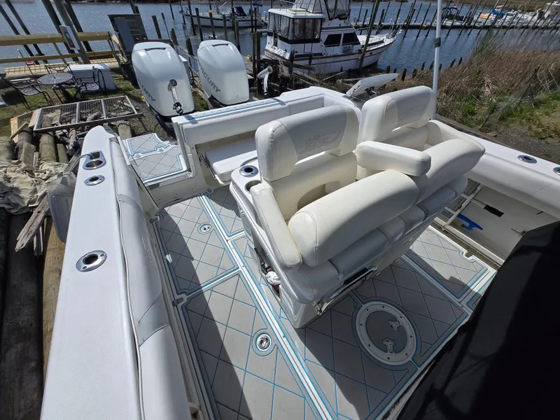 Slide: The Image of 2013 Boston Whaler 280 Outrage boat interior with white seating and dual engines docked at marina. - 22