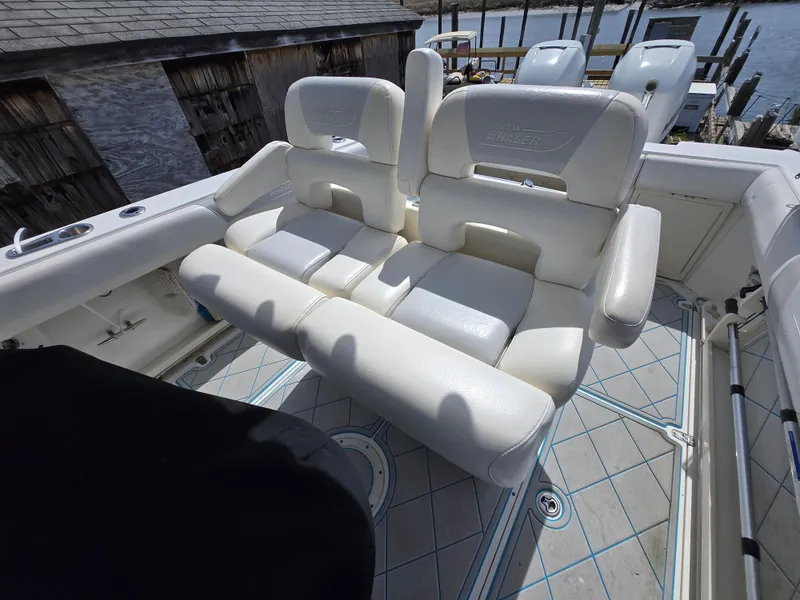 Slide: The Image of 2013 Boston Whaler 280 Outrage boat with white cushioned seating, docked by wooden structure. - 6