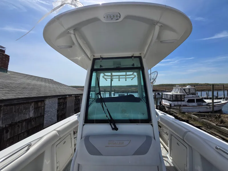 Slide: The Image of 2013 Boston Whaler 280 Outrage boat docked, showcasing helm and windshield under clear sky. - 7
