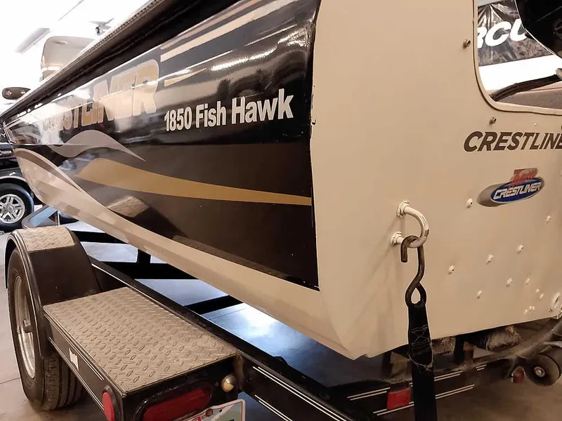 Slide: The Image of 2006 Crestliner 1850 Fish Hawk DC boat on trailer, showcasing sleek design and branding. - 10