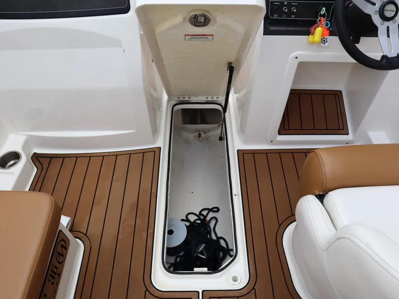Slide: The Image of 2022 Bayliner VR4 Bowrider Outboard interior with open storage compartment and steering wheel. - 19