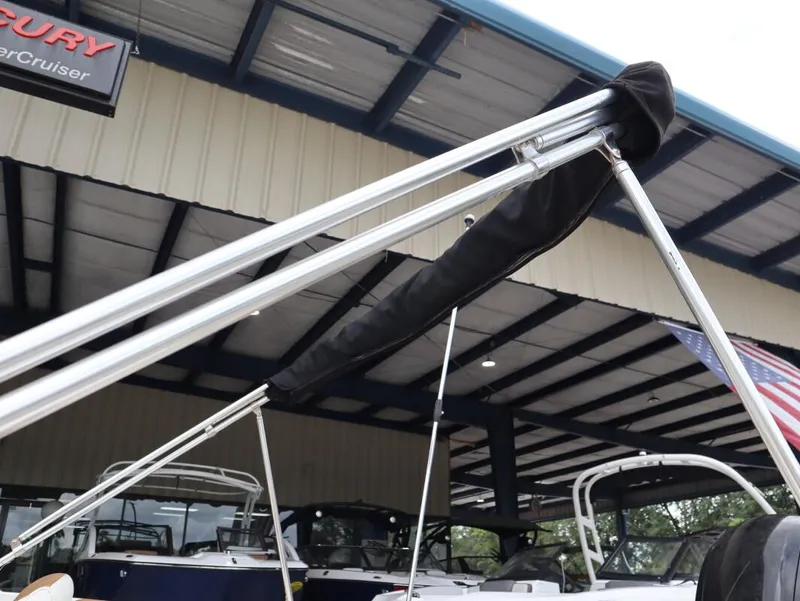 Slide: The Image of 2022 Bayliner VR4 Bowrider Outboard with bimini top under a metal roof. - 7