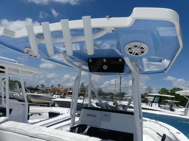 Slide: The Image of 2021 Blackfin 252CC boat with blue T-top and rod holders, docked under a clear sky. - 10