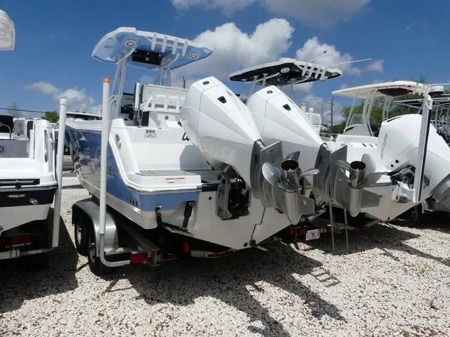 Slide: The Image of 2021 Blackfin 252CC boat with dual outboard engines, parked on gravel under a blue sky. - 3