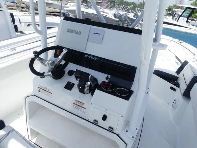 Slide: The Image of 2021 Blackfin 252CC boat console with steering wheel and controls at marina. - 9