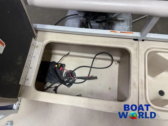 Slide: The Image of 2014 Sun Tracker Fishin Barge pontoon storage compartment with wiring, open hatch, Boat World logo. - 25