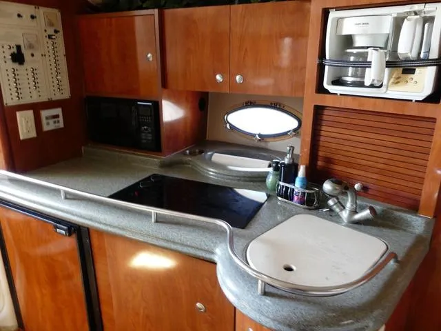 Slide: The Image of 2005 Larson 330 CABRIO yacht kitchen with stove, sink, and microwave. - 23