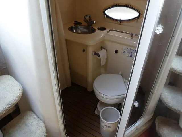 Slide: The Image of 2005 Larson 330 CABRIO boat bathroom with sink, toilet, and porthole window. - 24