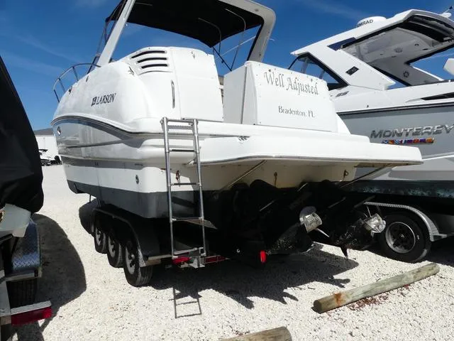 Slide: The Image of 2005 Larson 330 CABRIO boat, rear view, parked on gravel, with ladder and visible propellers. - 4