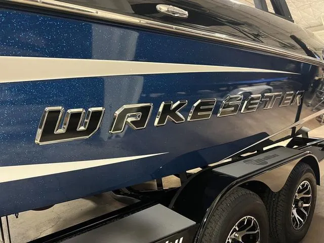 Slide: The Image of 2014 Malibu Wakesetter 22 MXZ boat with blue and white design on trailer. - 3
